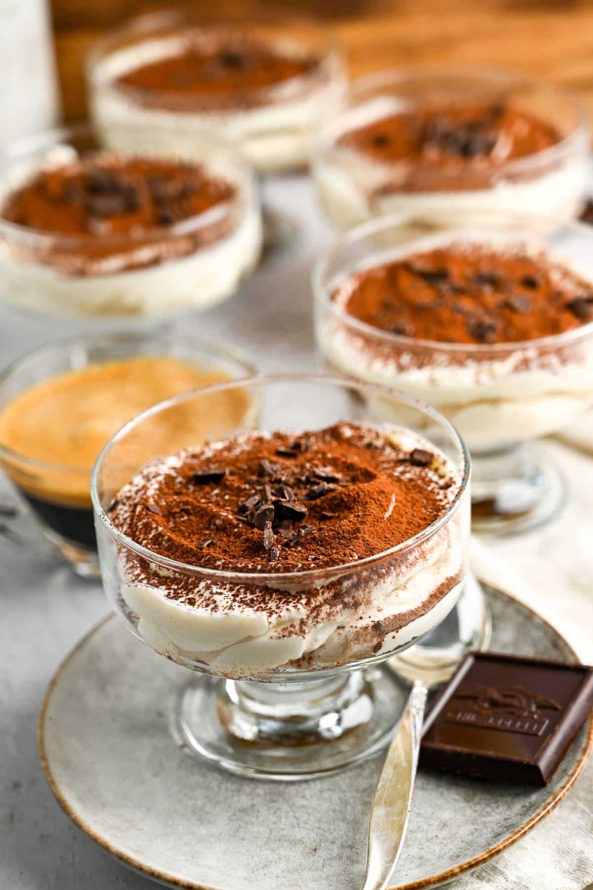 dishes of tiramisu with a piece of chocolate and spoon